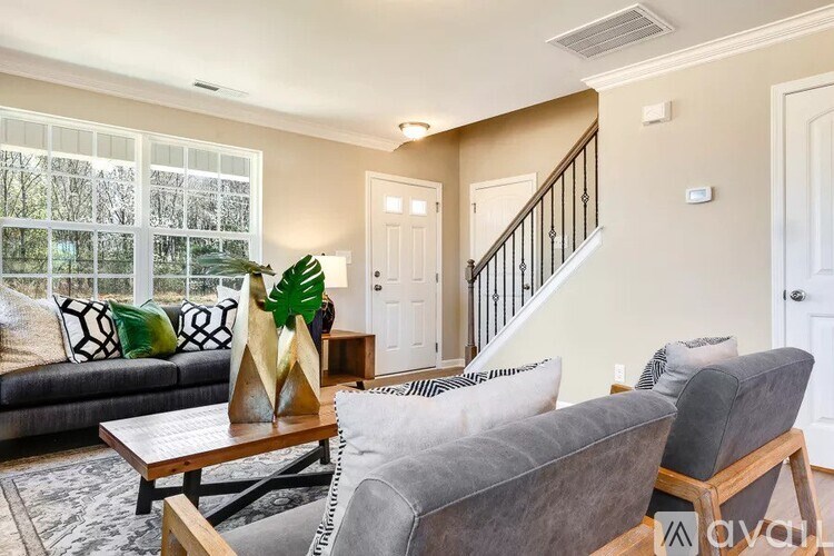 A living room with a grey couch, a wooden coffee table, and a staircase.
