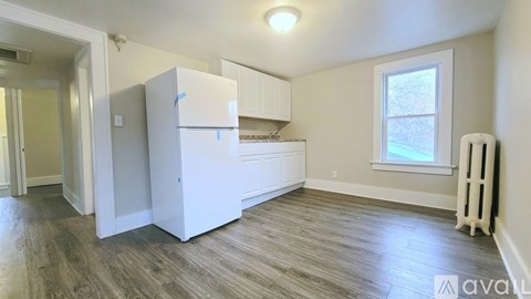 A small kitchen with a white fridge and wooden floors.