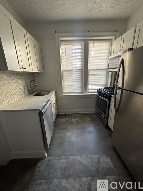 A kitchen with white cabinets and a stainless steel refrigerator.