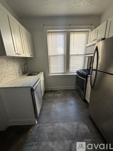 A kitchen with white cabinets and a stainless steel refrigerator.