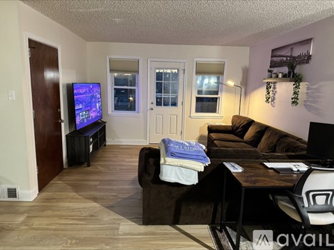 A living room with a brown couch and a television on a stand.