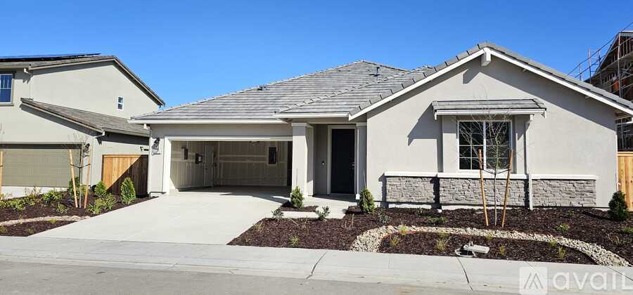 A house with a grey roof and a garage is for sale.