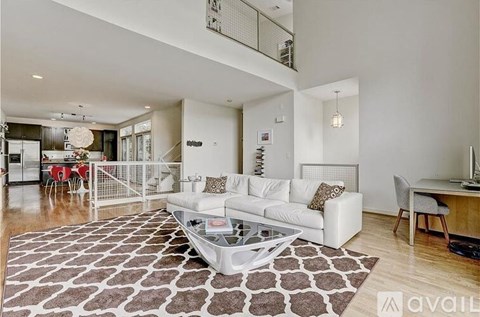 A living room with a white couch and a patterned rug.