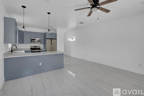 A modern kitchen with a marble floor and a ceiling fan.