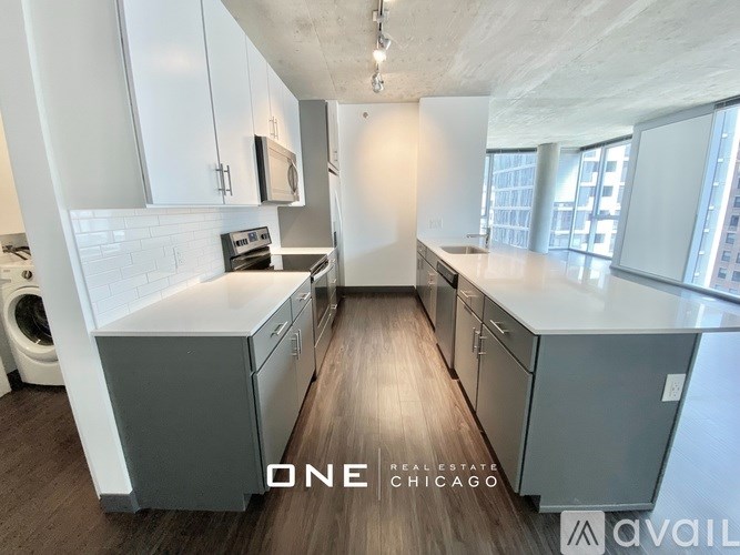 A modern kitchen with wooden floors and white cabinets.