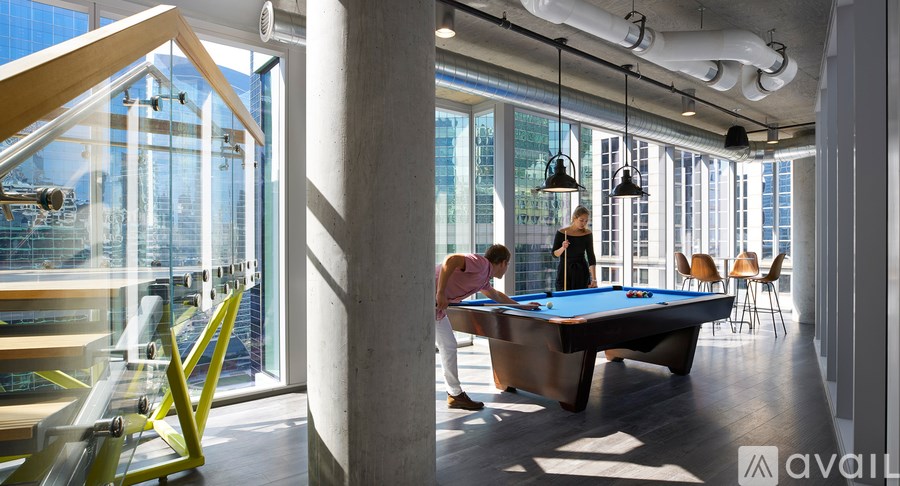 A pool table in a room with a person standing behind it.
