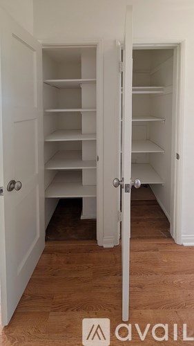 A white pantry with a door open to a hallway.