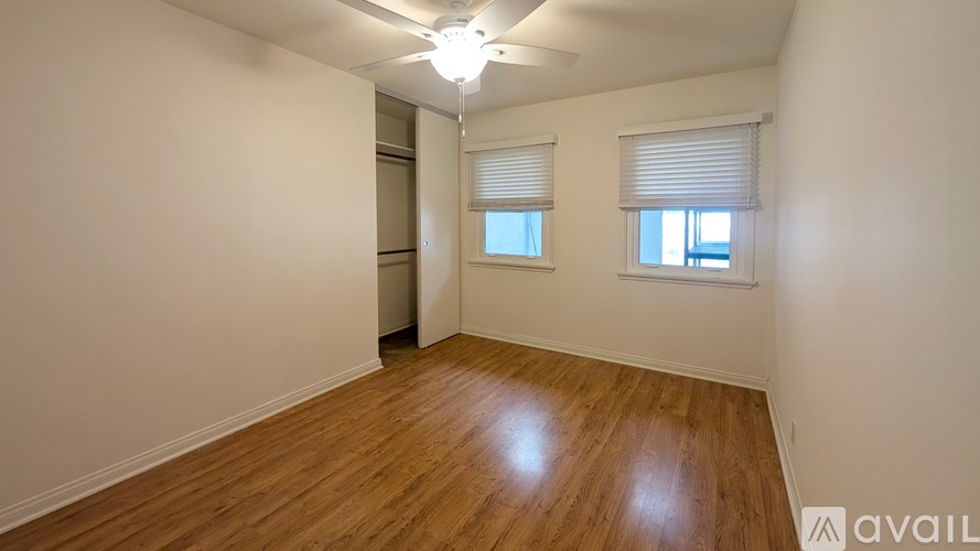 A room with wooden floors and a window with blinds.