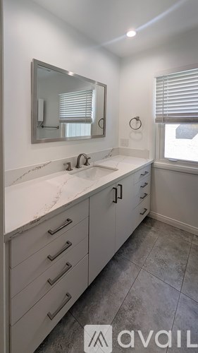 A bathroom with a marble countertop and a large mirror.