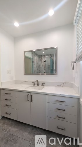A bathroom with a sink, mirror, and cabinets.