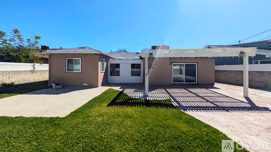 A house with a brown roof and a white garage door is surrounded by a green lawn.