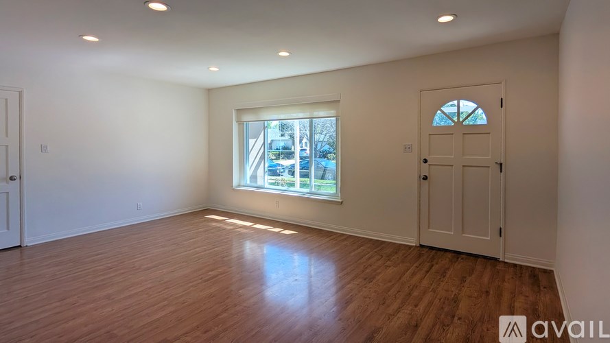 A room with wooden floors and a large window with a view of a city.