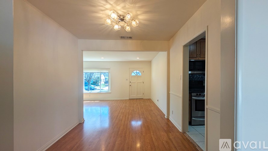 A spacious room with wooden floors and a chandelier.