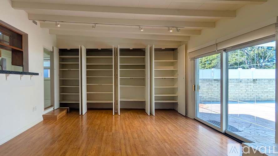 A room with a lot of shelves and a wooden floor.