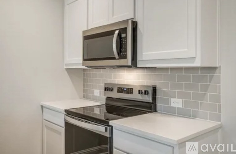 A kitchen with white cabinets and a black microwave above the stove.