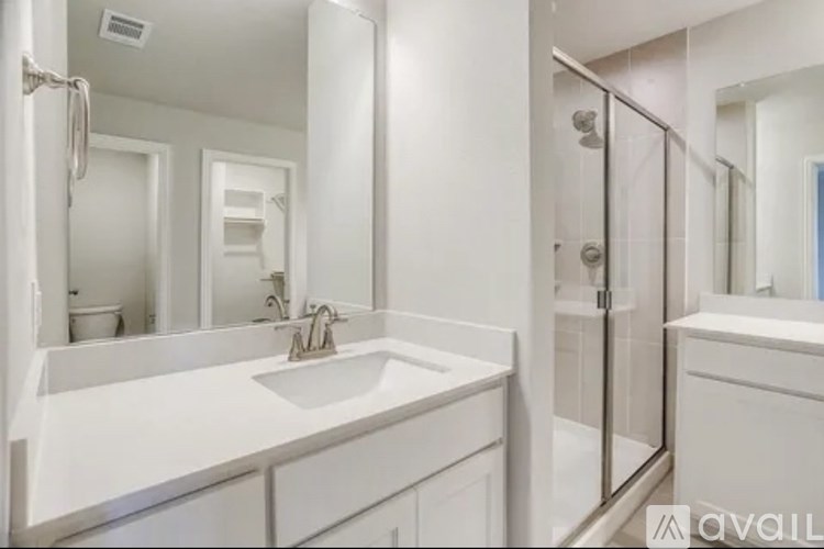 A bathroom with a sink, mirror, and shower.