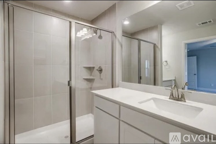 A modern bathroom with a white sink and a glass shower stall.