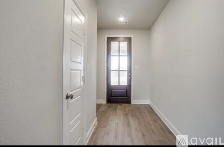 A hallway with a door on the left and a window on the right.