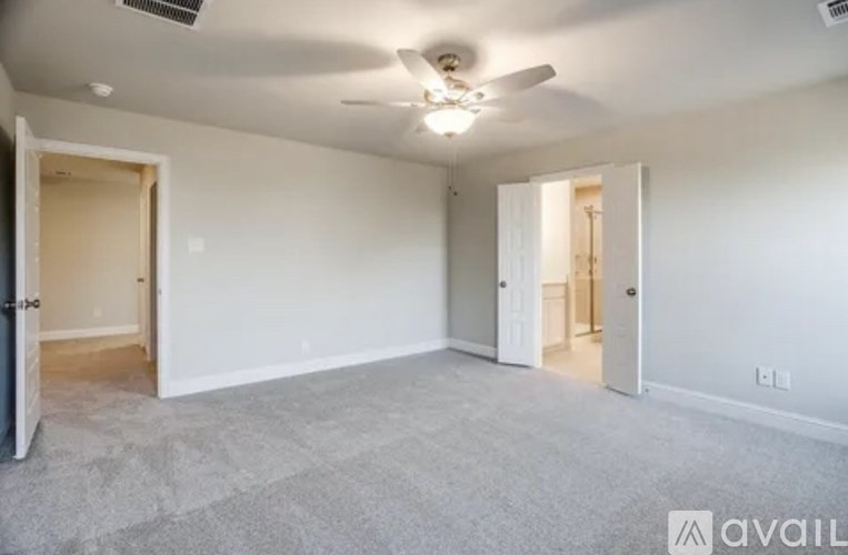 A spacious room with a ceiling fan and carpeted floor.