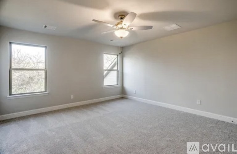 A room with a ceiling fan and two windows.