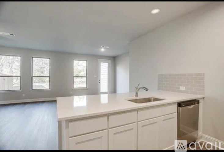 A kitchen with white cabinets and a countertop with a sink and dishwasher.
