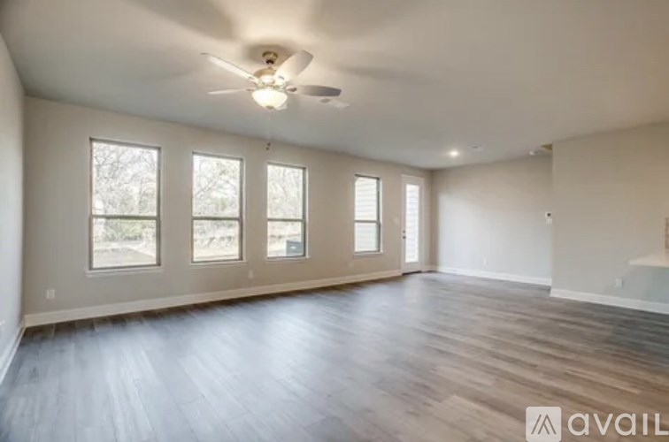 A spacious room with wooden flooring and a ceiling fan.