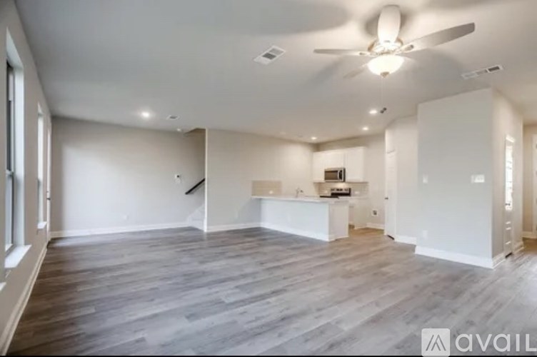A spacious room with a ceiling fan and wooden flooring.