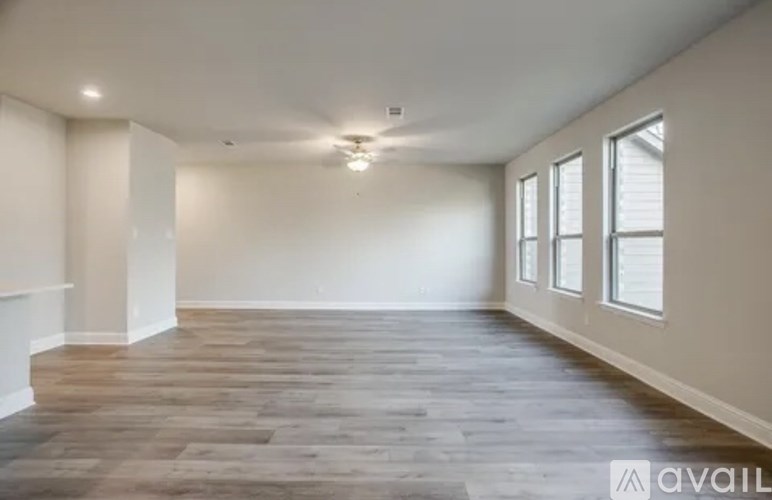 A spacious room with wooden flooring and a row of windows on one wall.