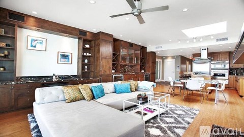 A living room with a grey couch and a fan.