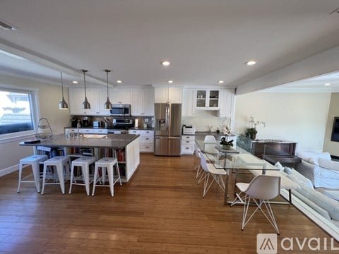 A modern kitchen with white cabinets and a wooden floor.