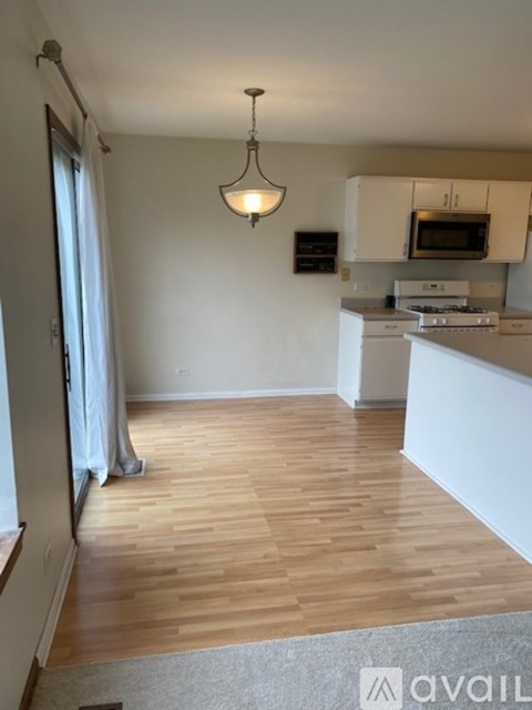 A kitchen with white cabinets and a wooden floor.
