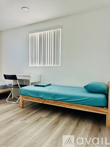 A bedroom with a bed, desk, and chair.