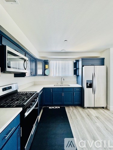 A kitchen with blue cabinets and a white refrigerator.