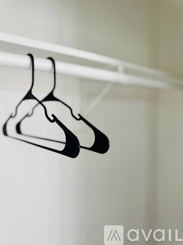 Two black hangers hanging on a white rod.