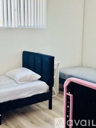 A bed with a white pillow and a black headboard is in a room with a pink bed frame.