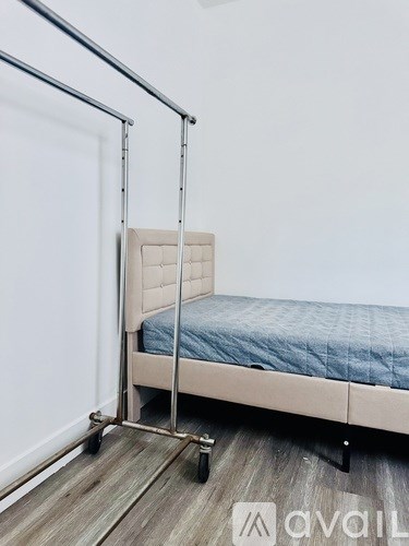 A bed with a metal frame and a blue mattress is positioned in a room with a white wall.