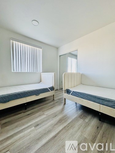 A bedroom with two beds and wooden flooring.