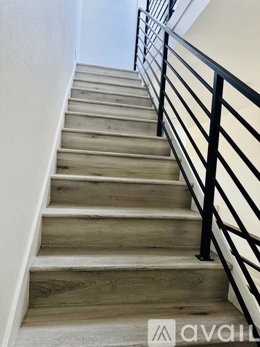 A set of stairs with a black railing and wooden steps.