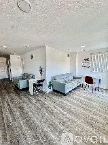 A living room with a grey sofa and a white desk.