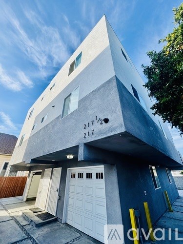 A modern house with a white garage door and a blue wall.