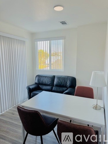 A living room with a black leather couch, a white table, and a lamp.