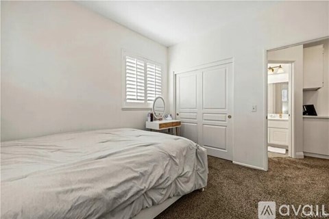 A bedroom with a bed, a nightstand with a lamp, and a closet.