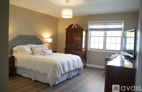 A bedroom with a large bed and a wooden dresser.