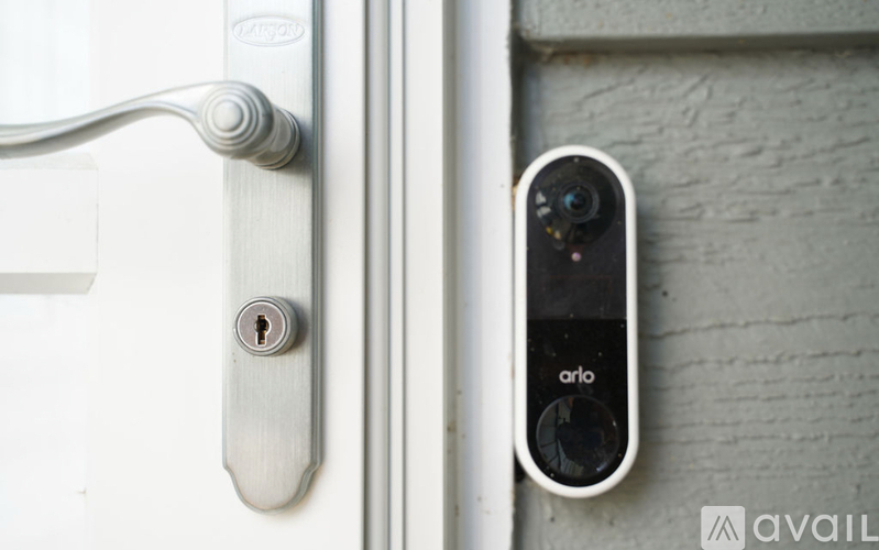 A door handle with a keyhole and a camera labeled "arlo" attached to the door.
