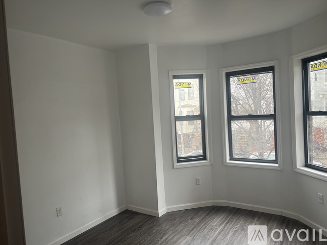 Three windows in a room with white walls and wood flooring.