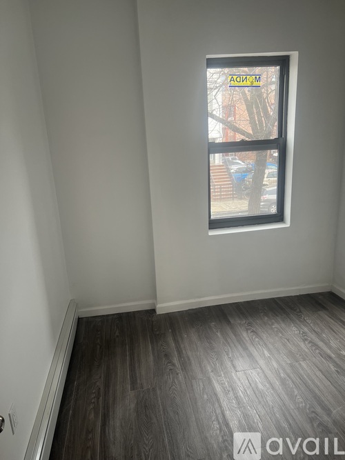 A room with a window and wooden flooring.
