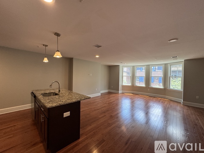 A spacious kitchen with a granite countertop and wooden flooring.