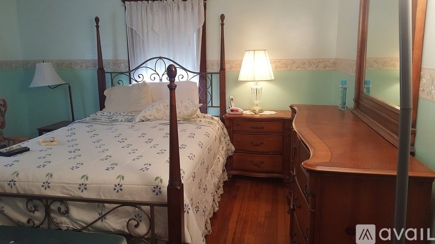 A bed with a white comforter and a wooden nightstand with a lamp on it.
