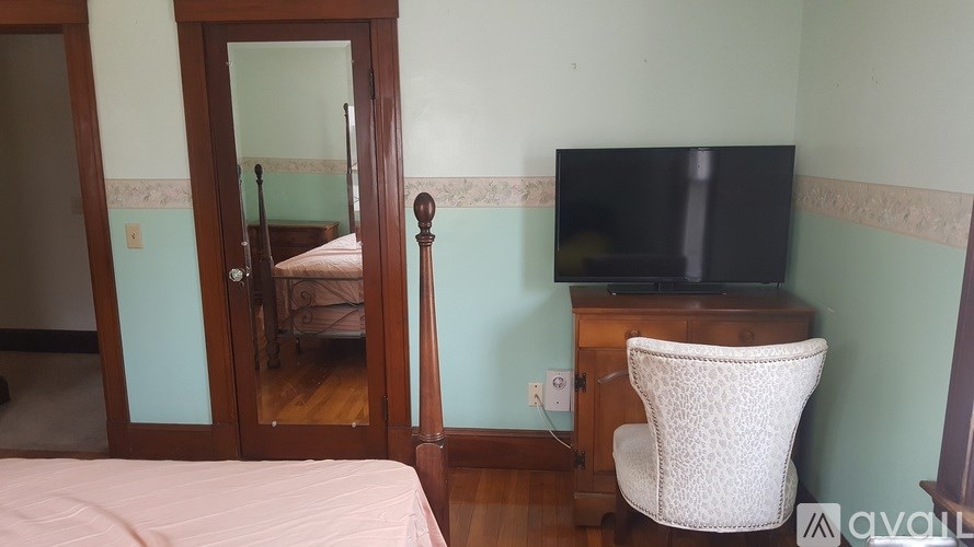 A bedroom with a bed, chair, and television.