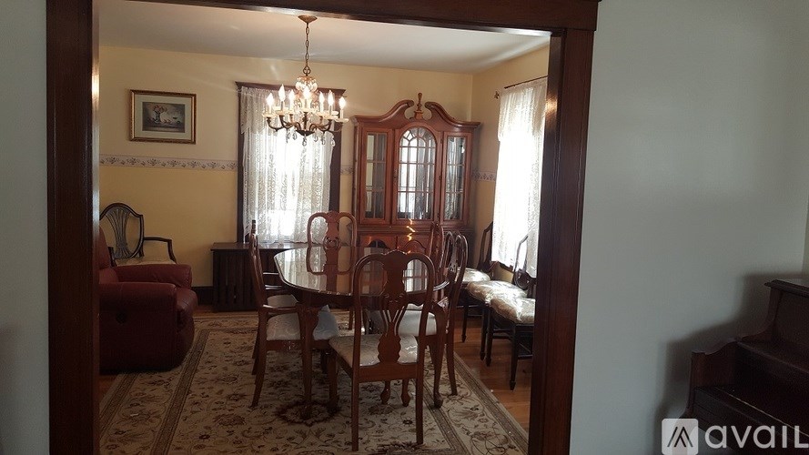 A dining room with a chandelier, a table with chairs, and a framed picture on the wall.
